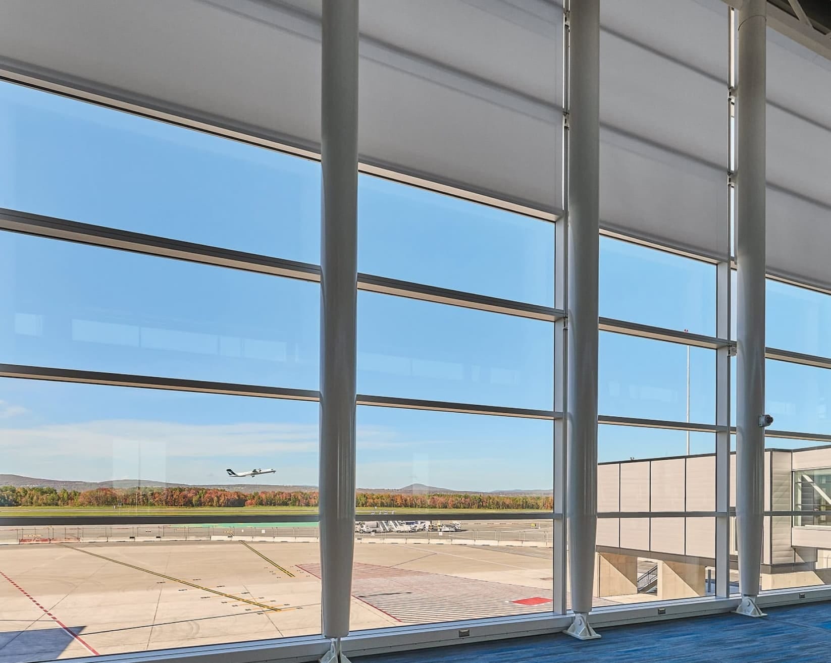 Large-scale roller shades installed across an airport curtain wall