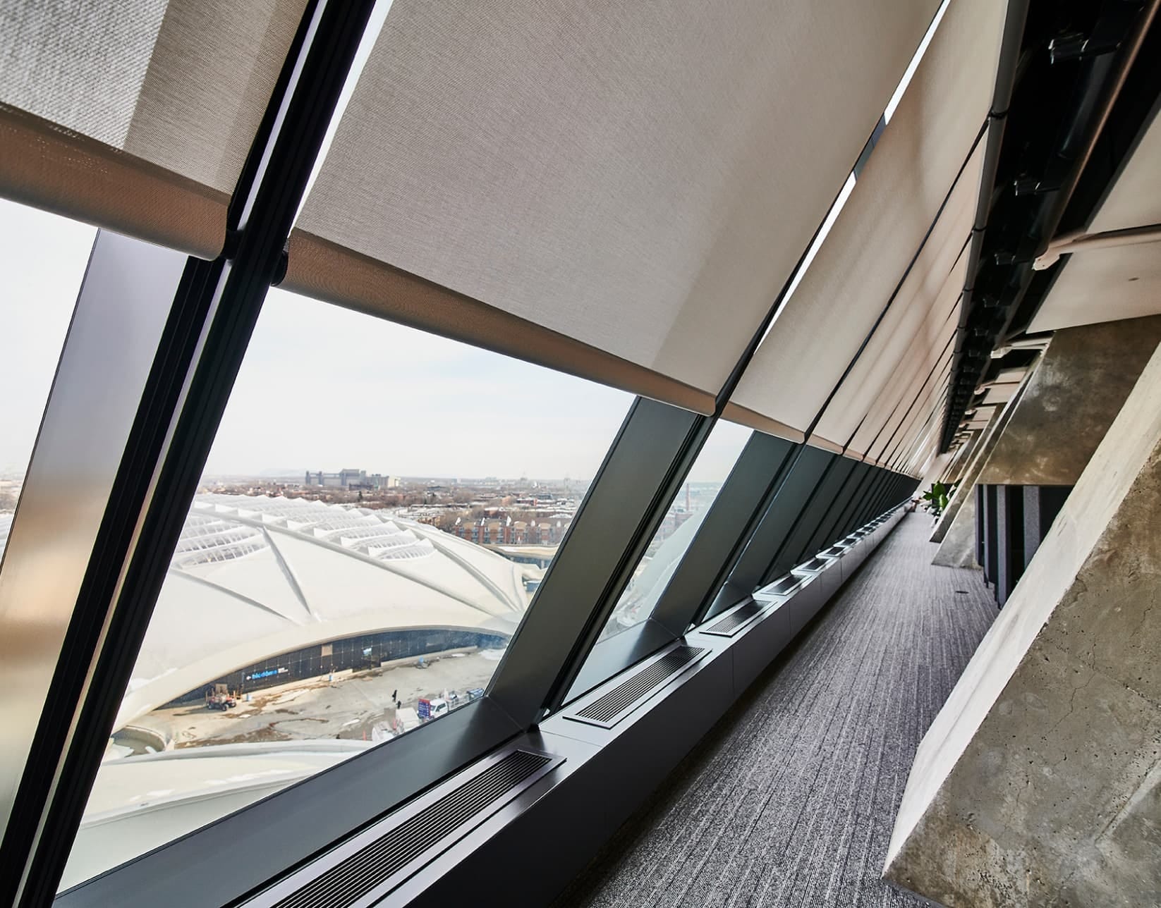 Architectural roller shades fitted to a large sloped glass façade